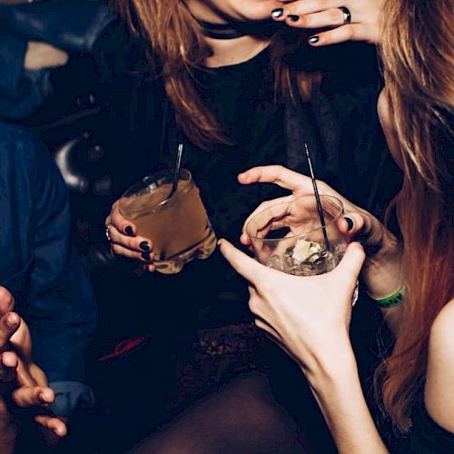 People are enjoying a social gathering with drinks in hand, engaging in lively conversation and laughter.