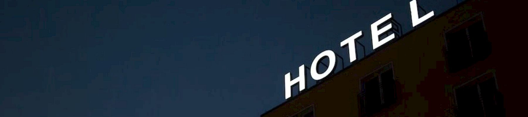 A building with the word "HOTEL" in white letters on top, but the "E" is missing, against a dark sky.
