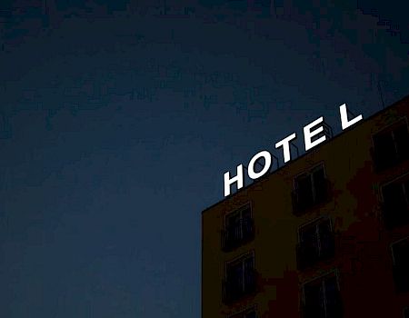 A building with the word "HOTEL" in white letters on top, but the "E" is missing, against a dark sky.