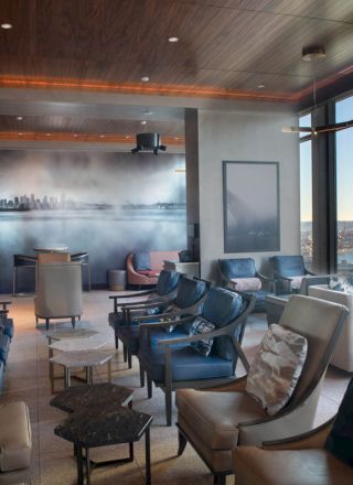 A modern lounge with comfortable seating, large windows, and a scenic view of the water and a Ferris wheel.